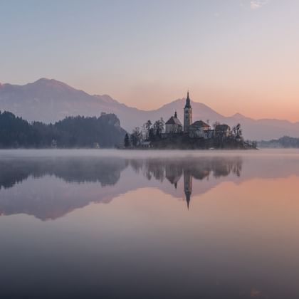 Eine Kirche steht auf einer kleinen Insel auf einem See in den Bergen Sloweniens.