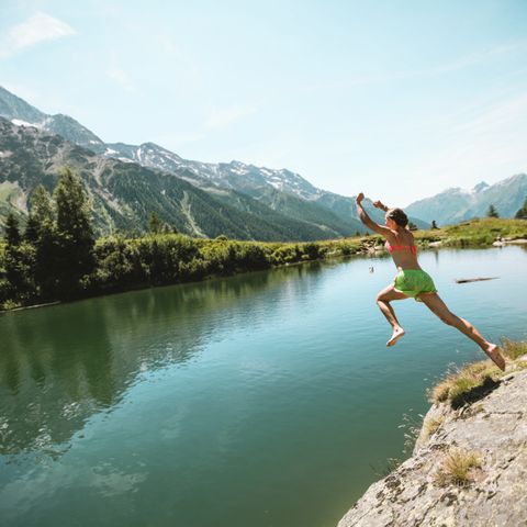 Eine Frau springt von einer Klippe in den Schwarzsee.