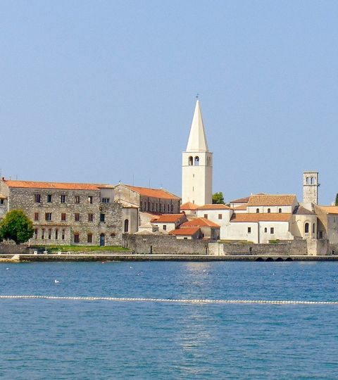 Auf dem Meer sieht man die Kirche auf der Halbinsel von Porec. 