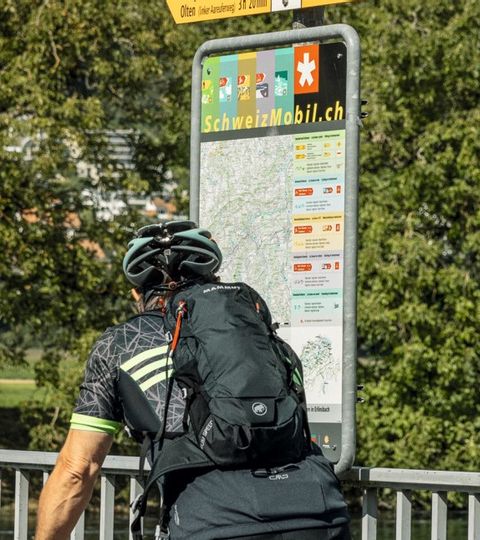 Velofahrer schauen auf der SchweizMobil Tafel die Route ihrer Tour nach. 