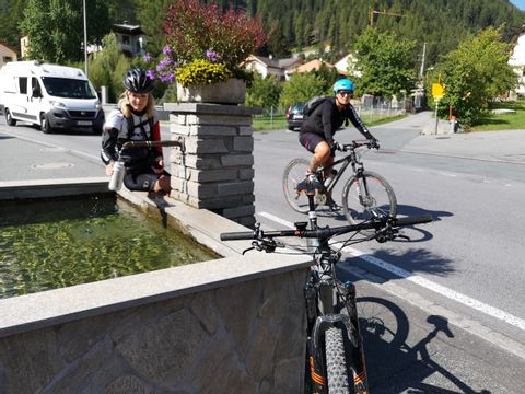 Zwei Biker füllen ihre Wasserflaschen an einem Brunnen auf ihrer Biktour durch den Schweizerischen Nationalpark.