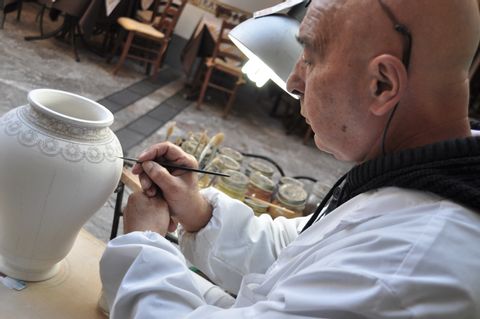 Ein Maler bemalt einen Tontopf auf Sizilien.