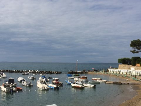 In der Bucht die mit einer Steinmauer im Wasser vom offenen Meer abgetrennt ist, sind viele kleine Boote festgemacht. 