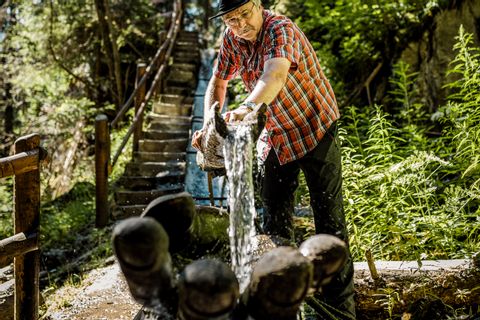 Wanderer schöpft Wasser im Wald mit Hilfe eines Naturbehälters