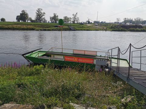 Ein kleines Fährboot steht an einem Steg, dass über den Fluss führen soll. 