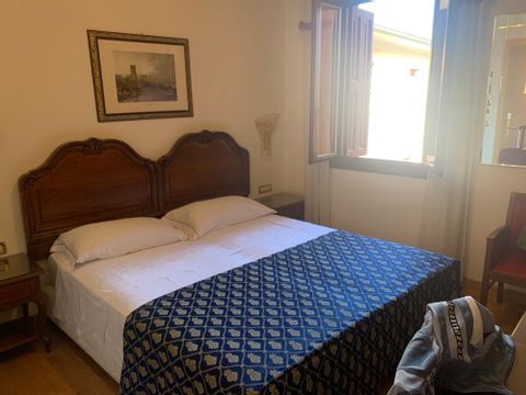 Ein Holzbett im Zimmer des Hotels Spossatto in Portogruaro. 
