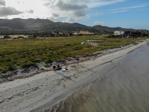 Ein paar Menschen befinden sich an einem einsamen Strand auf Sardinien mit Grünflachen im Hintergrund.