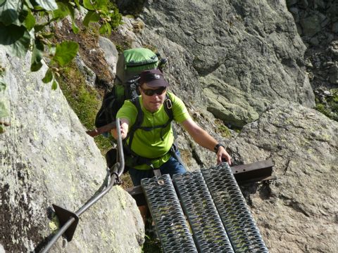 Wanderer erklimmt eine Metalltreppe, die zur Bergbesteigung dient.