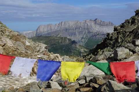 farbenfrohe Wimpel im Wind mit Bergpanorama im Hintergrund
