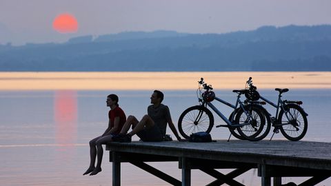 Cyclistes profitant du coucher de soleil sur une passerelle. Itinéraire sur l'Aar. Vacances à vélo avec Eurotrek.