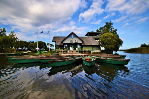 Ein Bootshaus, das am Steg mit Ruderbooten belagert ist.