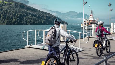 Deux cyclistes poussent leur vélo jusqu'à l'embarcadère du bateau.