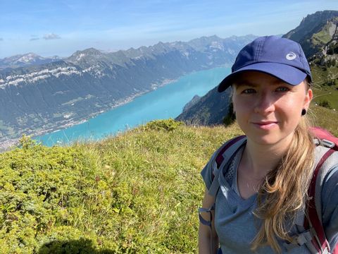 Nicole, employée d'Eurotrek, sur le sommet d'une montagne avec un lac en arrière-plan.