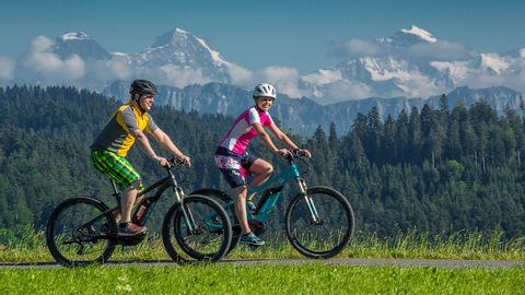 Two mountain bikers on a leisurely ride in front of the mountain landscape.