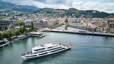 A white ship named MS Diamant sails on Lake Lucerne. Behind it is the city of Lucerne.