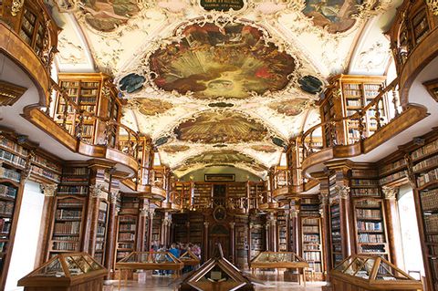 säuberlich geordnete Bibliotheke in einem Schloss mit Fresken an der Decke