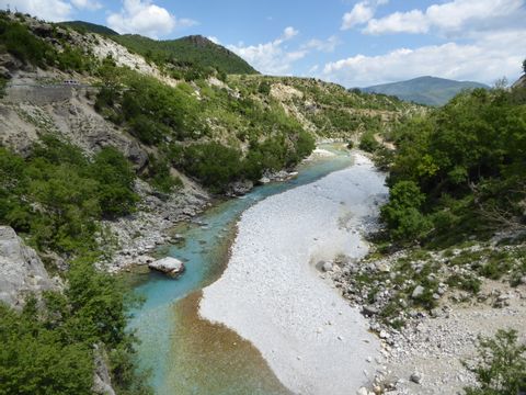 Ein kleiner Fluss zieht sich durch die weiten Landschaften auf einer Wanderung durch Albanien.