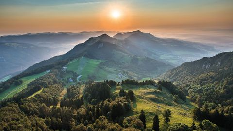 Atemberaubender Sonnenaufgang auf dem Weissenstein der den Hommel am Horizont in ein zartes orange färbt und den Berg und die Hügel in verschiedene grüntöne versetzt