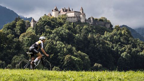 Cyclistes devant une colline densément boisée avec un château