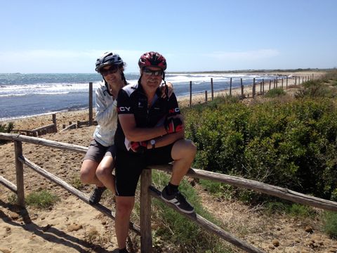 Die zwei Radfahrer sitzen auf einem Holzzaun vor der Meeresküste von Sizilien.