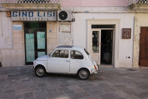 kleiner weisser Fiat Punto parkiert vor Geschäft