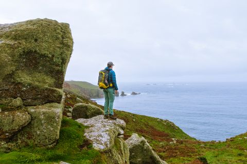 Wanderer geniesst Blick aufs Meer bei Land's End in Cornwall bei stürmischem Wetter.