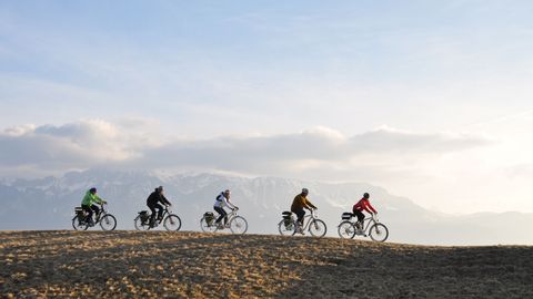 Cinq cyclistes à l'horizon, roulant l'un derrière l'autre.