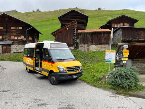 Ein Postauto hält in einem Bergdorf zum Start der Wanderung des Alpenpässewegs. 
