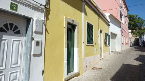 Einer schmalen Gasse entlang, stehen Reihenhäuschen, deren Fassaden in Pastellfarben angemalt sind.