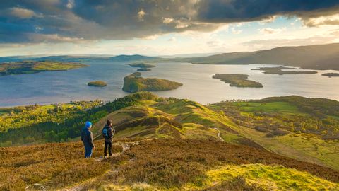 Deux randonneurs contemplent le lac Loch Lomond en Écosse