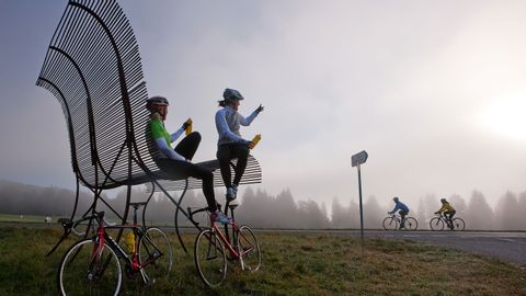 zwei Radfaherinnen sitzen auf einer Riesen Bank