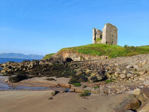 Eine Burgruine steht am Strand in Irland 