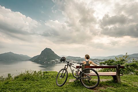 Une cycliste profite de la vue sur le lac de Lugano. Lugano à vélo. Vacances à vélo avec Eurotrek.