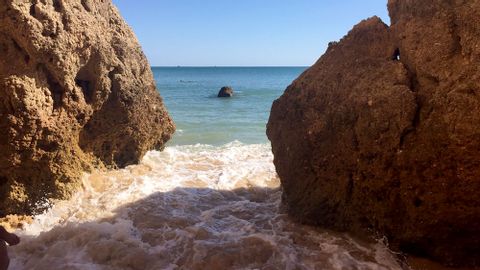 Kleine Strandschläuse zwischen zwei Felsen unter strahlend blauem Himmel.