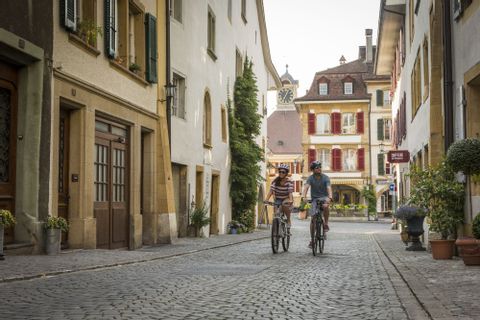 Zwei Velofahren fahren durch die Altstadt von Murten mit dem Velo. 