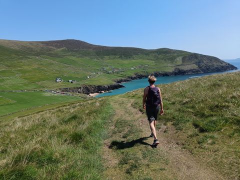 A hiker in front of a bay in the background green hills 