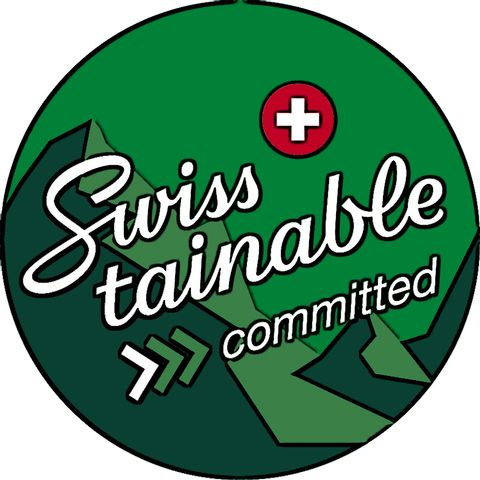 Ein rundes In zwei verschiedenen grün tönen mit der Aufschrift "Swisstainable" in weisser Schrift auf einem Berg im Hintergrund. Rechts über der Schrift ist das Schweizer-Wappen in runder Form.