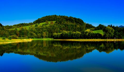 Eine wunderschöne Landschaft unter strahlend blauem Himmel, die sich im See spiegelt.