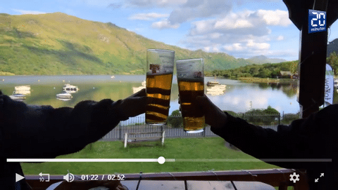 Zwei Personen stossen mit einem Bier an mit einem See im Hintergrund. Aktivferien mit Eurotrek.