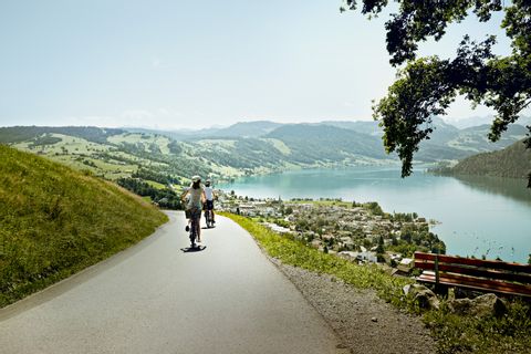 Two cyclists on a side road, travelling downhill towards Lake Zug.