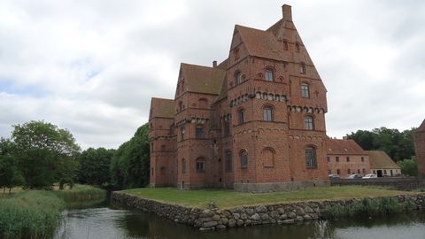 Grosses Kirchenähnliches Gebäude mit Sichtmauerwerk auf einer Insel in einem kleinen See.