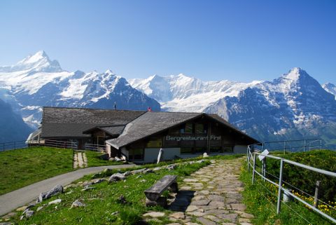 Maison dans un paysage de montagne avec des sommets enneigés en arrière-plan