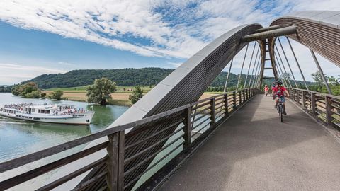 Velofahrer überqueren einen Fluss auf der Fribourg Region Rundfahrt.
