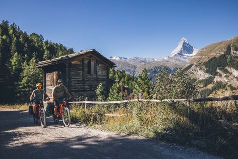 Zwei Velofahrer auf einer Schotterstrasse im Hintergrund das Matterhorn. 