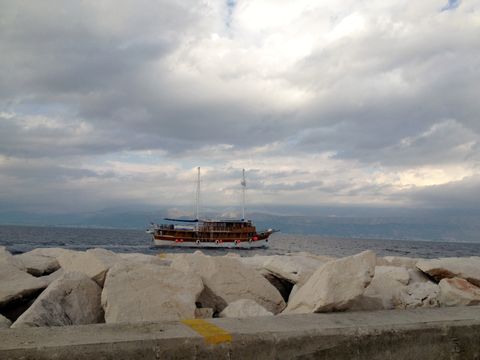 Einsames Fischerboot an der Küste von Dalmatien, unter stark bewölktem, grauem Himmel.