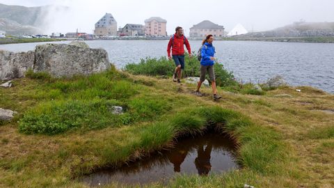 2 Wanderer gehen dem Ufer des Sees auf dem Gotthardpass entlang.