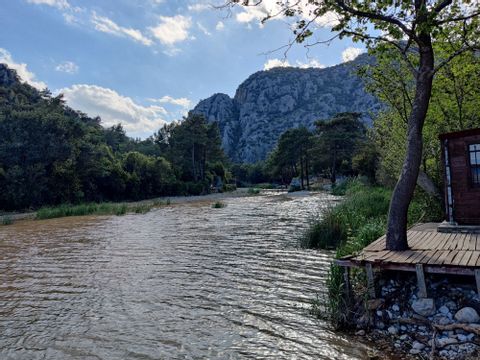 Fluss mit Bäumen am Ufer vor türkischer Bergkulisse 