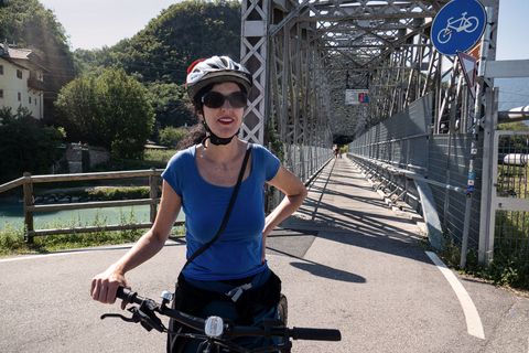 Eine Radfahrerin steht mit ihrem Rad vor einer Brücke, welche ausschliesslich für Radfahrer ist.