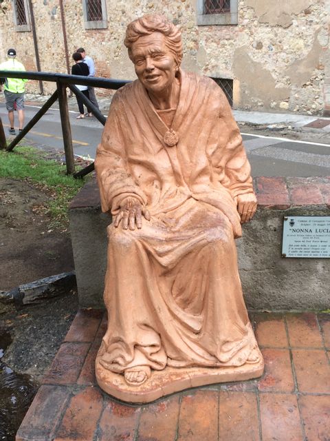 Eine sitzende Steinfiguer in der Farbe Terracotta der Nonna Lucia.