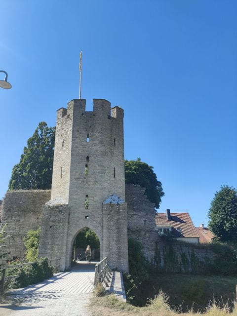 Eine Velofahrerin fährt durch den Turm einer Mittelalter Burg in Gotland. 